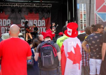 People wearing red or Canadian flags watch a band performing on a stage