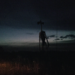 A tall monster is visible on the horizon at dusk.