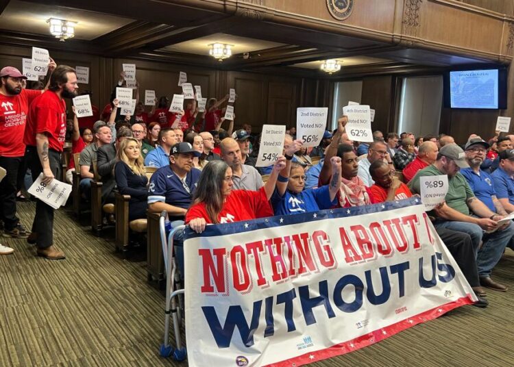 Members of Stand Up KC and the Missouri Workers Center pack Kansas City Council chambers on Thursday to oppose the passage of a financing deal for a new Royals stadium. Sitting behind and around them are members of the building trades unions, who support the deal.