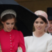 Princess Beatrice and Princess Eugenie wearing pink dresses walk down the steps into the garden of Buckingham Palace