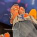 Feet in silver sandals next to Knicks logo on floor.