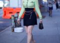 Person walking on a city sidewalk in a stylish outfit with a smile.