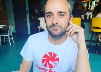 Caleb Willdee, an executive producer for Love Island USA, wearing a white t-shirt with a red "Pretty Swede Records" logo.