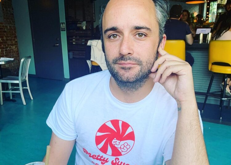 Caleb Willdee, an executive producer for Love Island USA, wearing a white t-shirt with a red "Pretty Swede Records" logo.
