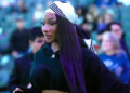Megan Thee Stallion wearing a black outfit and a striped headscarf, walking in a crowd.