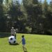Two people playing with a giant soccer ball on a grassy field.