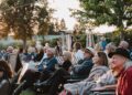 Audience members listen as singers and songwriters perform as part...