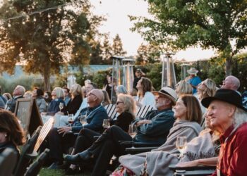 Audience members listen as singers and songwriters perform as part...