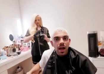 A person with bleached hair is sitting in a salon chair, while a hairstylist with long blonde hair prepares hair dye behind them.