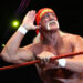 Hulk Hogan in a wrestling ring, wearing a red bandana and posing with a hand to his ear, showcasing his iconic mustache.