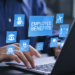 A employee sitting at a desk using a laptop with a graphic over the top saying "Employee Benifits".