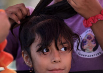 Luna Rodriguez, 7, waits to get colored hair extensions by...