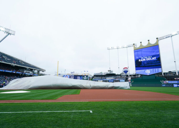 KANSAS CITY, MO - APRIL 15: Members of the grounds crew adjust the tarp during a rain delay before the Kansas City Royals take on the Atlanta Braves at Kauffman Stadium on April 15, 2023 in Kansas City, Missouri. All players are wearing the number 42 in honor of Jackie Robinson Day. (Photo by Kyle Rivas/Getty Images)