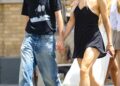 Rosalia wears a black mini dress with two feathers adorned to its straps and pointed-toe mules while holding hands with model Loli Bahia on a date in Manhattan
