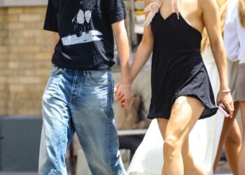 Rosalia wears a black mini dress with two feathers adorned to its straps and pointed-toe mules while holding hands with model Loli Bahia on a date in Manhattan