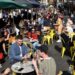 A large numbers of diners are pictured sitting at tables on OId Compton Street, Soho, in a large space lined with green awnings on either side