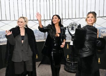 three women dressed in black wave to people behind and to the left of the camera
