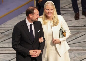 A man and a woman in formal attire looking on