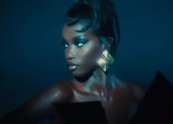 Person with metallic earrings in dim lighting, looking to the side.