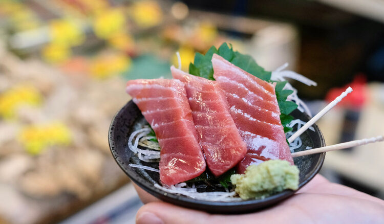 A hand holding fish tartare in Tsukiji Outer Market, Japan