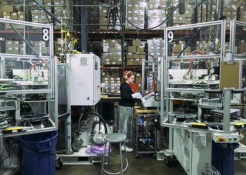 Soren Smith wears white headphones and a black sweatshirt while doing a vinyl record inspection.