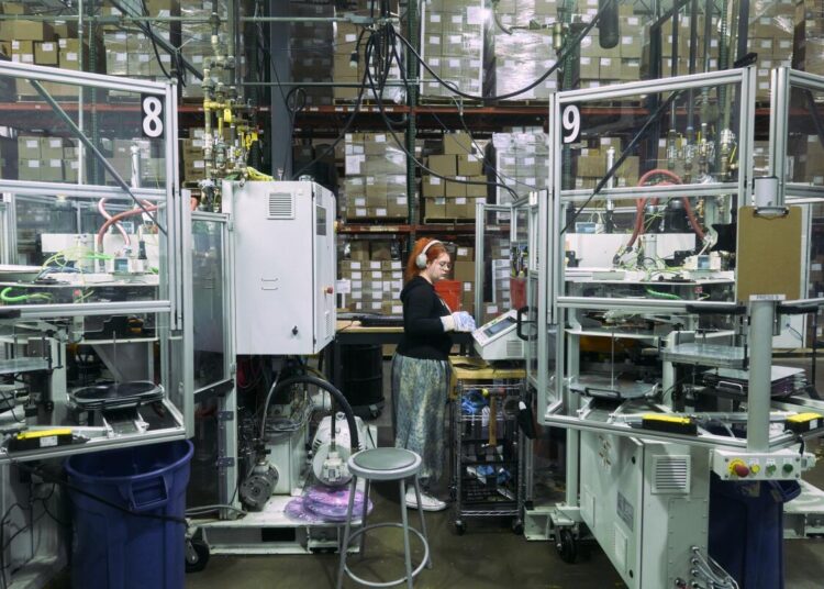 Soren Smith wears white headphones and a black sweatshirt while doing a vinyl record inspection.