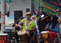 People play drums at an outdoor event.