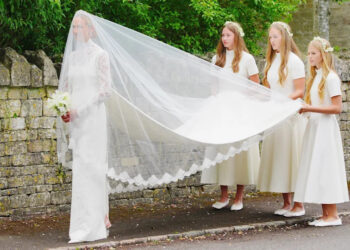 Bridesmaids hold veil outside church