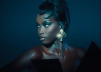 Person with metallic earrings in dim lighting, looking to the side.
