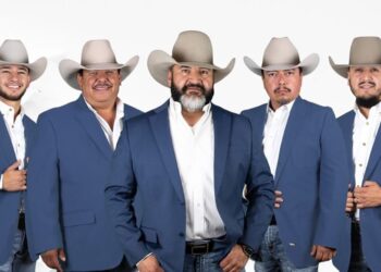Five members of Cautivo Norteño wearing blue blazers and cowboy hats pose together in a studio portrait.