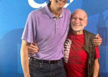 Two men pose for the camera in a side hug.