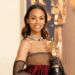 afro-latina actress poses with an Academy Award trophy at a red carpet event, celebrating her achievements in film.