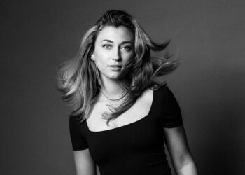 Martina Myskohlid faces the camera wearing a black dress, with her hair in motion.