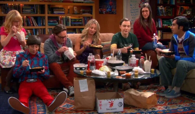 Sheldon sits in his spot while eating dinner with friends