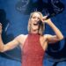Celine Dion singing into a microphone, wearing a red sequined sleeveless, high-neck dress