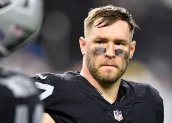 A football player in a black uniform with eye black, looking serious during a game.