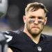 A football player in a black uniform with eye black, looking serious during a game.