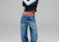 Model wearing a black crop top, light blue long-sleeve shirt, and wide-leg jeans, striking a pose.