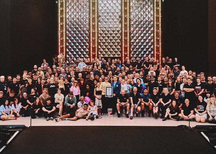Harry Styles on stage surrounded by his tour crew being presented a GWR certificate