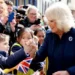 Queen Camilla in a blue coat shakes the hand of a schoolchild during her visit to the Isle of Man