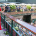 The Princess of Wales, in a red dress, waves to the crowd at Wimbledon as she walks across a bridge