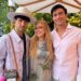 Three people celebrating a birthday outdoors, with festive attire and a decorative backdrop.