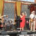 Band The New Feral Cats performing on an outdoor stage at a festival featuring guitarists, a vocalist and a drummer