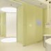 Modern medical room with pale yellow walls, circular lighting, and a sleek design featuring a treatment chair and equipment.
