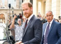Prince Harry leaving Chatham House in London with security behind him.