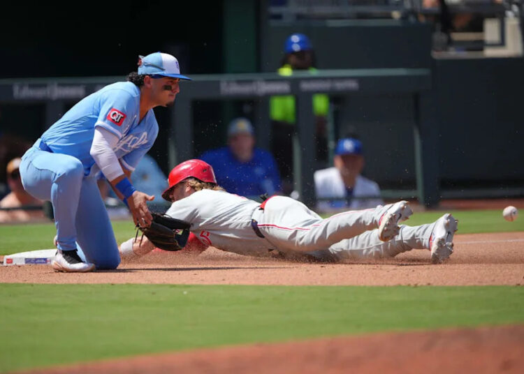 Philadelphia Phillies infielder Bryson Stott slides into third for a triple past Kansas City Royals third baseman Josh Rojas in the fifth inning at Kauffman Stadium on July 05, 2026 in Kansas City, Missouri.