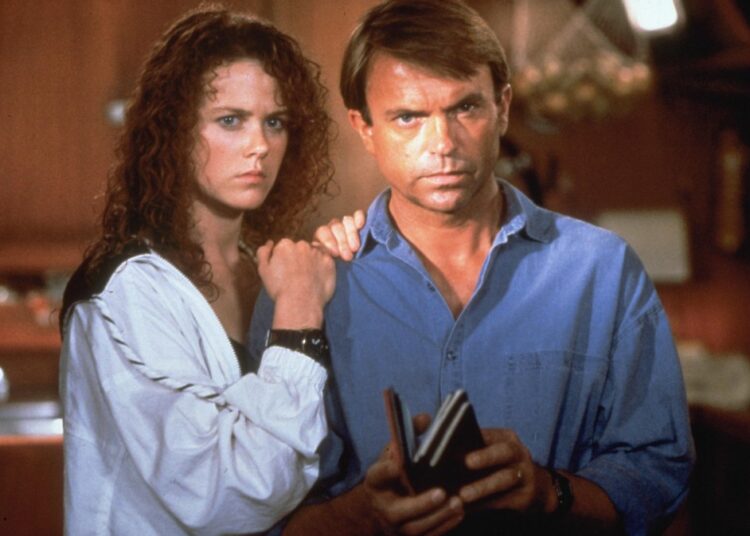 Nicole Kidman with curly red hair and Sam Neill in a blue shirt with a wary expression.