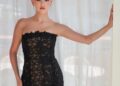 Selena Gomez poses in a strapless black dress with a subtly nude design featuring sheer panels with her hair worn in a high bun