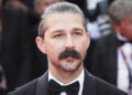 Shia LaBeouf with a mustache and slicked-back hair in a tuxedo at a formal event.