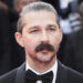 Shia LaBeouf with a mustache and slicked-back hair in a tuxedo at a formal event.